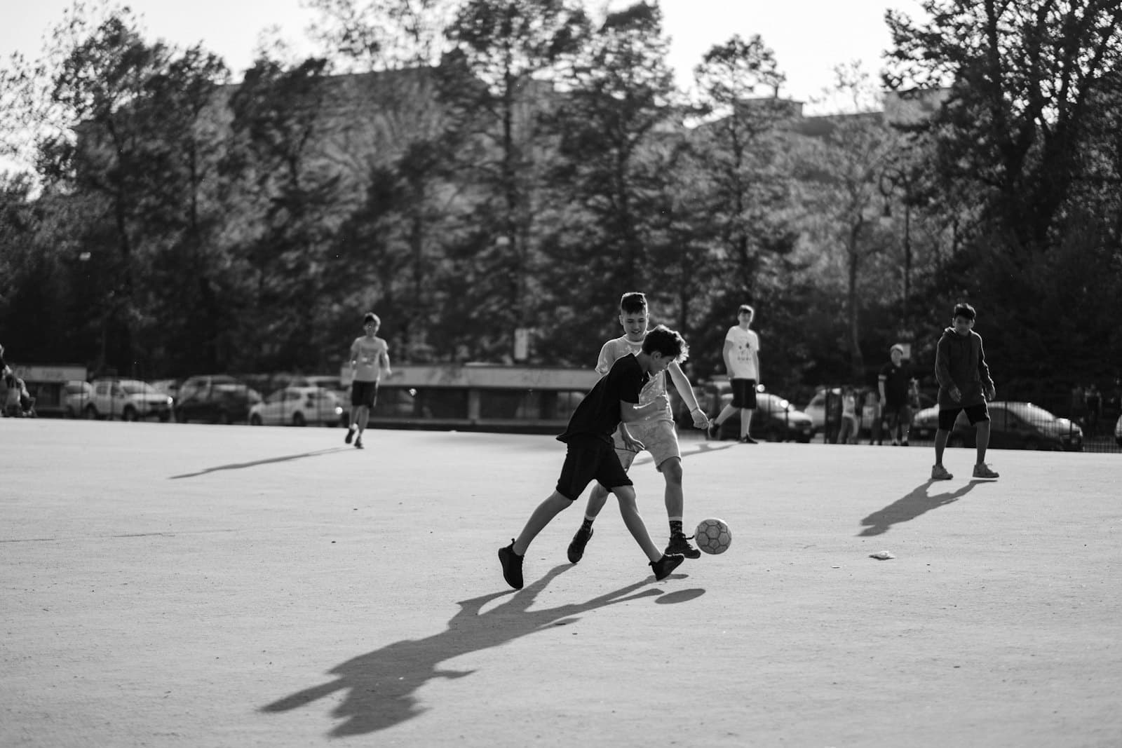 Boys playing football on an open concrete pitch