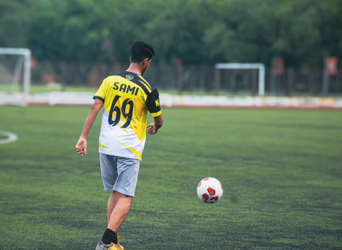 A young player in a yellow shirt running onto the ball at trials